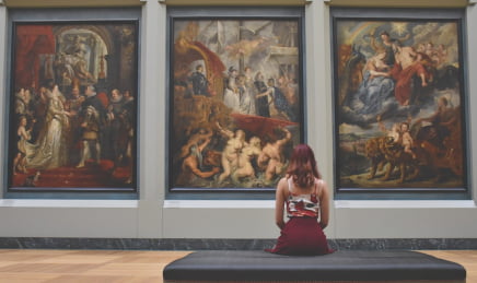 A redhead woman in an art gallery sitting on a bench
