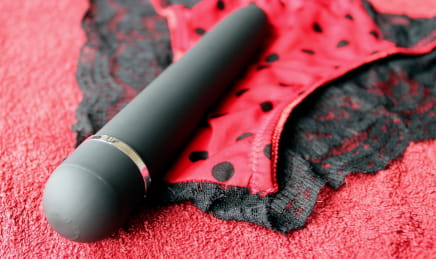 A black vibrator on top of red panties