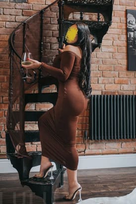 Curvy petite brunette holding a glass of wine and climbing a spiral staircase