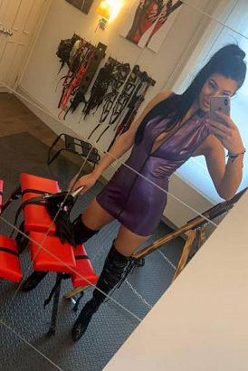 Tall London BDSM mistress in a fully kitted out dungeon taking a selfie
