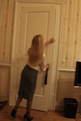 Petite blonde girl opening a big white door